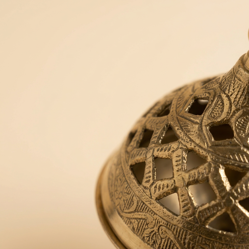Macro close-up of the pierced lattice cutwork and etching on a brass dhuni lid, framed in the corner